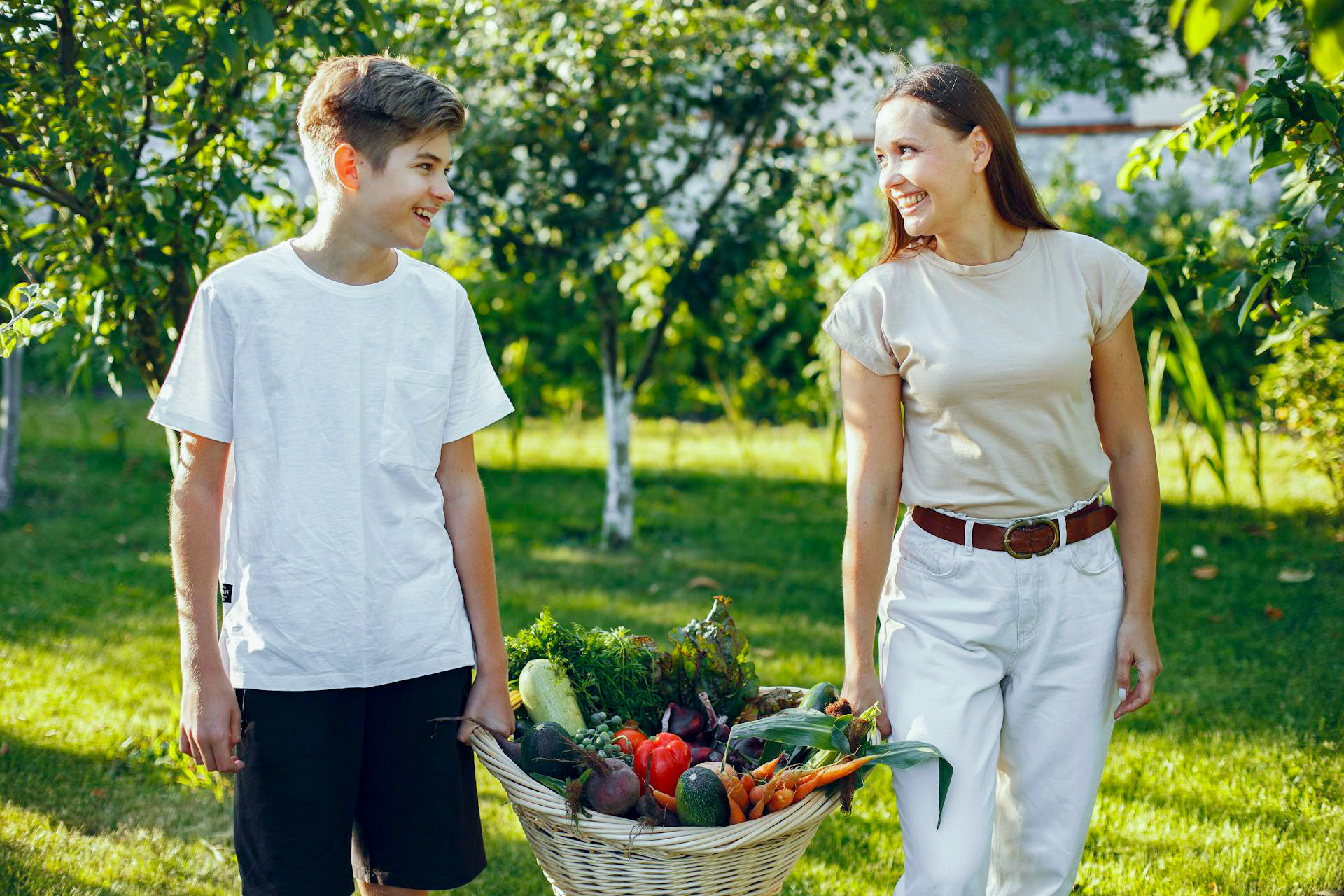 A mother and son carrying a basket of vegetables.